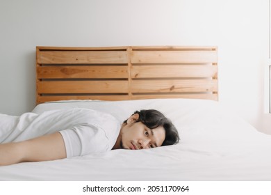 Exhausted Asian man lay on the bed as he feels burnout. Foto stock