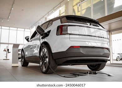Exterior of new brand fully electric suv car in light dealership. Battery charger in white electric car based in modern showroom with panoramic windows. Arkistovalokuva