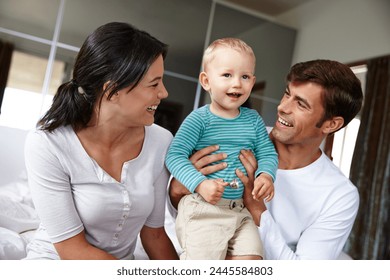 Family, happiness and parents with child in the home, love and security with parenting, childhood and bonding. Support, trust and care with man, woman and young boy in bedroom, smile and positivity 库存照片