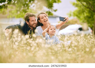 Family, selfie and nature with flowers, field and trees for bonding, love and social media together outdoor. Woman, kid and man playing at park in summer for happy, memory and post for live streaming 库存照片