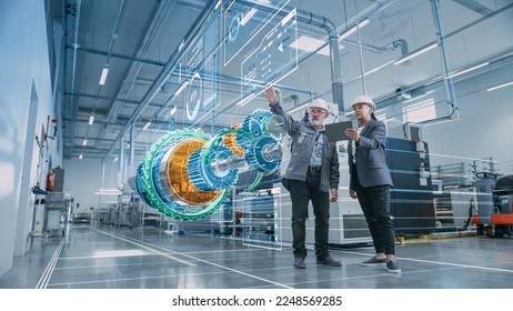 Factory Digitalization: Two Industrial Engineers Use Tablet Computer, Visualize 3D Model of Clean Green Energy Engine. Industry 4 High-Tech Electronics Facility with Machinery Manufacturing Products Stockfoto