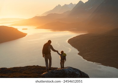 Father and child hiking in Norway traveling together summer vacations adventure trip healthy lifestyle outdoor active dad and daughter kid with backpack enjoying sunset fjord and mountains view  Foto stock