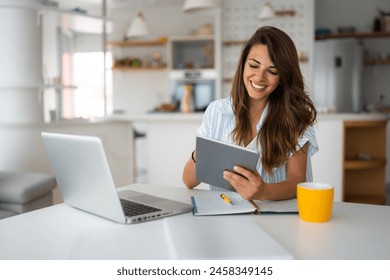 Female business person using digital tablet and laptop or remote working at home office, looking at digital tablet watching webinar, learning training, studying online seminar or video calling. Adlı Stok Fotoğraf