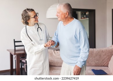Female professional doctor consulting senior patient during medical care visit. Young woman physician and old man talking providing medical assistance. Elderly people home care concept स्टॉक फ़ोटो