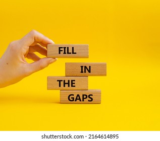 Fill in the gaps symbol. Concept words fill in the gaps on wooden blocks. Beautiful yellow background. Businessman hand. Business and fill in the gaps concept. Copy space. 庫存照片