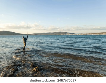 パイク、パーチ、鯉のための釣り。ロッドを持つ漁師、海や海の上にリールを回転させます。男は魚を捕まえ、海で釣りをしながら竿を引っ張って、池。ワイルド・ネイチャー。田舎の別荘のコンセプト。背面。の写真素材