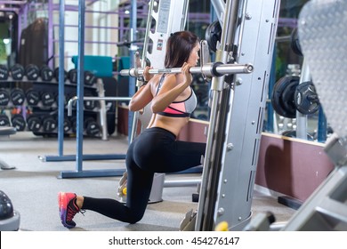 Fit girl doing lunges with the smith machine Foto Stock