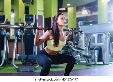 Fit woman doing squat with barbell in the gym Foto Stock