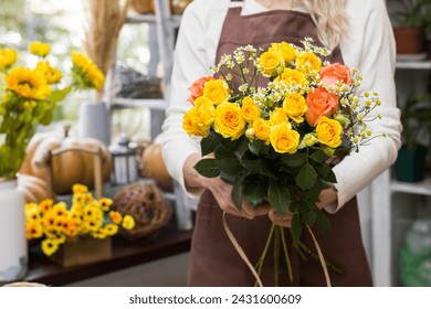 Florist holding a bouquet in a flower shop.Bouquet in the hands of a flower shop seller.Flower seller in an apron.floristry and flower arrangement training courses.Bouquet in hands close-up Stock-foto