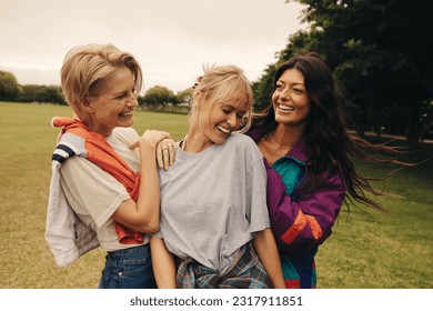 Friends enjoying a fun day of socializing at the park, bonding over laughter and playful activities. Three happy women enjoying each other's company. This photo has intentional use of 35mm film grain. – Ảnh có sẵn