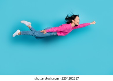 Full length photo of adorable purposeful lady wear pink pullover flying air hurrying help isolated blue color background Foto stock