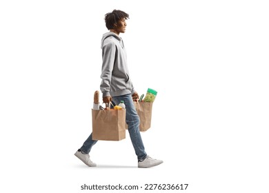 Largo disparo de un joven afroamericano llevando bolsas de compras y caminando aislado sobre fondo blanco Foto de stock