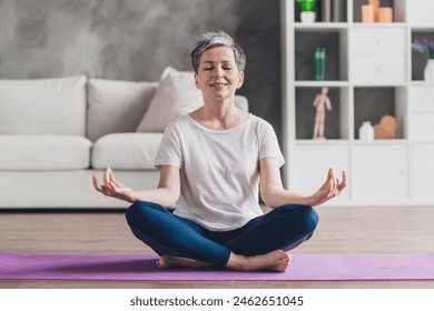 Full size photo of nice retired woman sit mat meditate sportswear sport healthy lifestyle workout modern apartment home living room 庫存照片