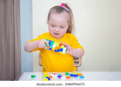 Chica con síndrome de Down jugando con Pequeños detalles del conjunto de construcción, desarrollo temprano. Foto de stock