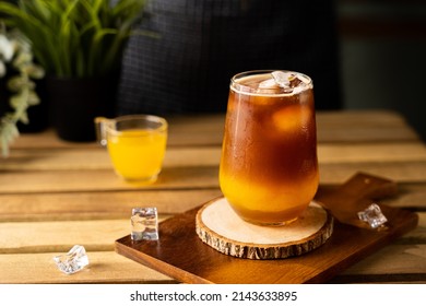 Glass of espresso with orange juice on wooden table and copy space, Summer Cocktail, Cold brew coffee or black tea. (close up, selective focus),Pouring cold drink. ஸ்டாக் ஃபோட்டோ