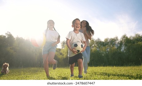 ボールで遊ぶ子供たちのグループ。楽しい夏のサッカーのコンセプト。子供たちの家族が走ってボールで遊んでいます。ライフスタイルの家族が走り回ってボールをプレーする子供たちのグループ。の写真素材