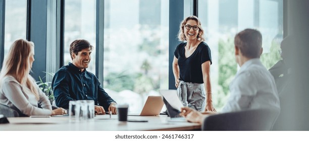Group of colleagues engaging in a discussion during a business meeting in a conference room. Happy business people, men and women, collaborating and working towards their shared goals. Foto stock