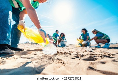 Group of eco volunteers picking up plastic trash on the beach - Activist people collecting garbage protecting the planet - Ocean pollution, environmental conservation and ecology concept Stock Photo