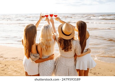 한 무리의 여자 친구들이 와인 잔을 부딪치며 함께 시간을 보낸다. 해변에서 파티를 할 때. 휴가, 휴식, 휴가, 피크닉. 스톡 사진