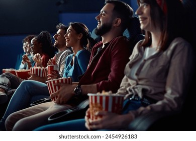 Group of people watching comedy movie in cinema. Focus is on woman laughing and eating popcorn.  Foto stock