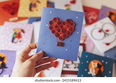 Hand holding quilling card with red heart balloon. Happy valentine day. woman making greeting cards. Hand made of paper quilling technique. Hobby, home office. Heart from red paper ribbons Stock-foto