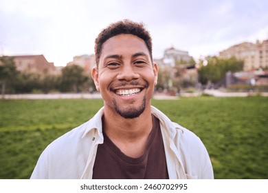 Handsome happy African American bearded man. Portrait of cheerful young man standing outdoors and smiling at camera. Positive emotion concept of male person. Generation z guy look carefree and natural Stockfoto