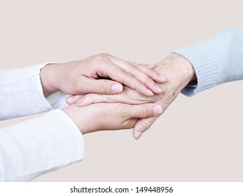 hands of a young woman holding the hand of an elderly woman. 库存照片