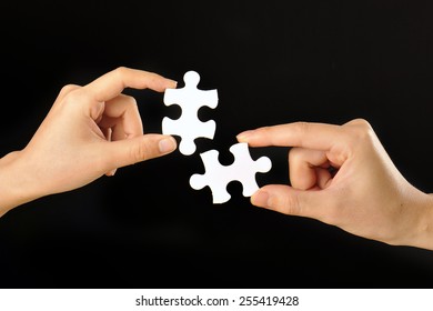 The hands of human beings that have a jigsaw puzzle that was taken with a black background Foto stock