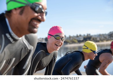 Happy triathletes in wet suits and goggles preparing for competition: stockfoto