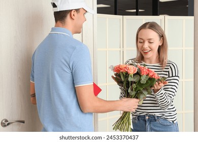 Happy young woman receiving bouquet of flowers from courier at door – Ảnh có sẵn