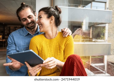 Happy young woman sharing tablet pc with boyfriend at home Arkistovalokuva