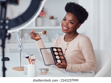 happy young african american woman streaming a beauty vlog from home, online content creator applying a makeup on Arkistovalokuva