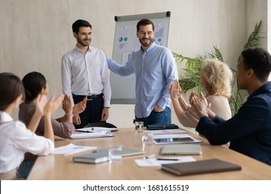 Happy young businessman introduce new male employee newcomer at office meeting, man boss congratulate worker with promotion or achievement, colleagues applaud, acknowledgment concept Arkistovalokuva