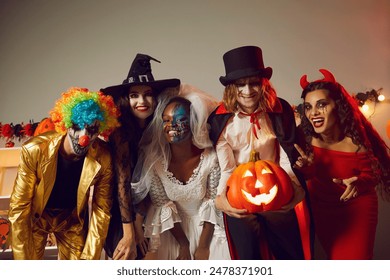 Happy young people dressed up as different spooky characters, with scary makeup on faces having fun at Halloween costume party. Group portrait of adult friends with traditional smiley jack-o-lantern Stock-foto