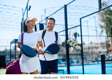 Happy athletic woman and her friend going to play paddle tennis on outdoor court. Copy space.  स्टॉक फ़ोटो