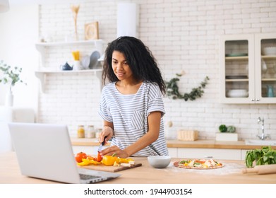 料理を楽しみ、撮影を楽しむ幸せな美しい二人暮らしの女性。現代のキッチンのノートパソコンでレシピを探し、食べ物ブロガーのコンセプト、健康的なライフスタイル、オンライン学習料理の授業コンセプトの写真素材