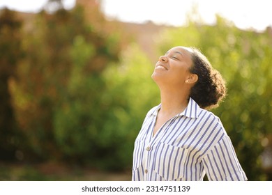 Happy black woman breathing fresh air standing in a park Foto stock