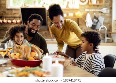 Happy black family having roast turkey for lunch while celebrating Thanksgiving at home.  Stock Photo