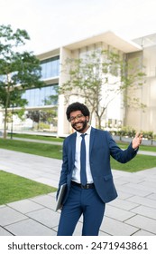 Happy businessman gesturing and standing with laptop in office park: zdjęcie stockowe