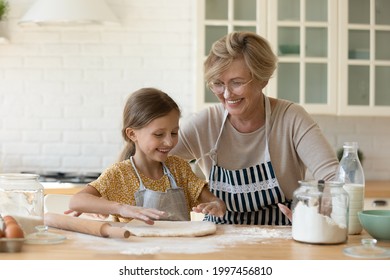 現代の台所で一緒に手作りのパストリーを作るなど、さまざまな世代の幸せな女性家族が楽しみを味わう。可愛いおばあさんと料理の腕前を分かち合う楽しいおばあさん。の写真素材