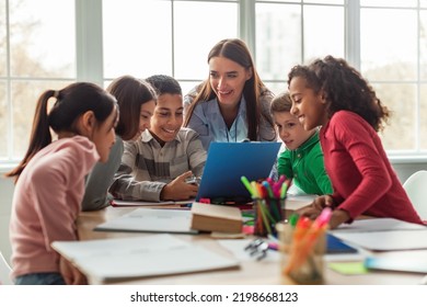 幸せな多様な学校の子供や教師女性のクラスを持って学校で教室の机に座って。現代教育と知識の概念。限定フォーカスの写真素材