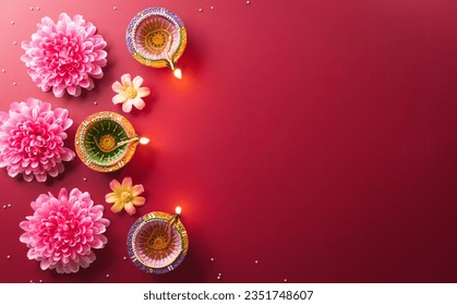 Happy Diwali - Clay Diya lamps lit during Diwali, Hindu festival of lights celebration. Colorful traditional oil lamp diya on red background Stock Photo