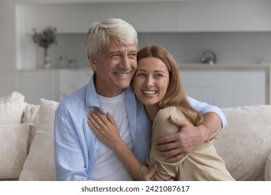Happy elderly father hugging cheerful adult pretty daughter child with love, laughing, looking away with good thoughts, toothy smiles, talking, thinking, enjoying relationship, bonding, fatherhood Stock-foto