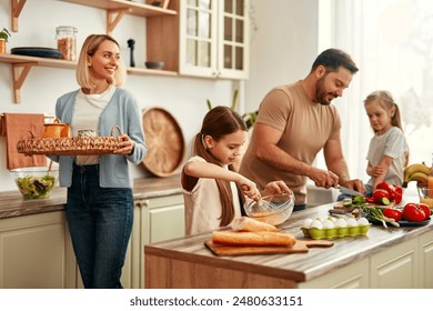 A happy family is cooking together in a bright kitchen, showing joy, teamwork, and love for homecooked meals, creating a warm and loving atmosphere at home Foto Stock