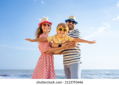 Happy family having fun on the beach. Mother and father holding son against blue sea and sky background. Summer vacation concept, fotografie de stoc