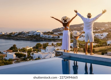 A happy family on summer holidays stands by the swimming pool and enjoys the beautiful sunset behind the mediterranean sea in Greece, fotografie de stoc