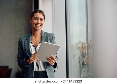 Happy female entrepreneur using touchpad while working in the office and looking at camera. Copy space. Adlı Stok Fotoğraf