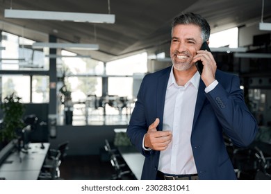 Happy mature business man ceo standing in office talking on cell phone. Middle aged businessman professional executive manager holding smartphone making corporate call communicating with client. Foto stock