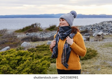 A happy mature woman in a yellow sweater walking in a chilly seaside in winter day.Concept: cheerful spirits, winter seascape, cozy style Foto stock