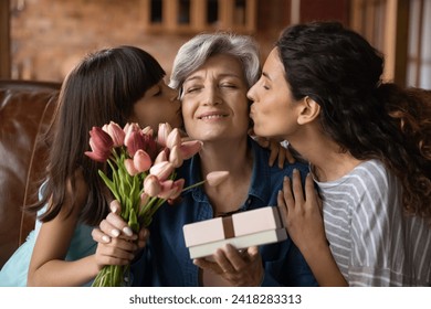 Happy Mothers Day. Affectionate young adult woman daughter and little kid girl granddaughter greeting excited mature latin lady mommy grandmother with birthday holiday kiss give flowers present gift – Ảnh có sẵn